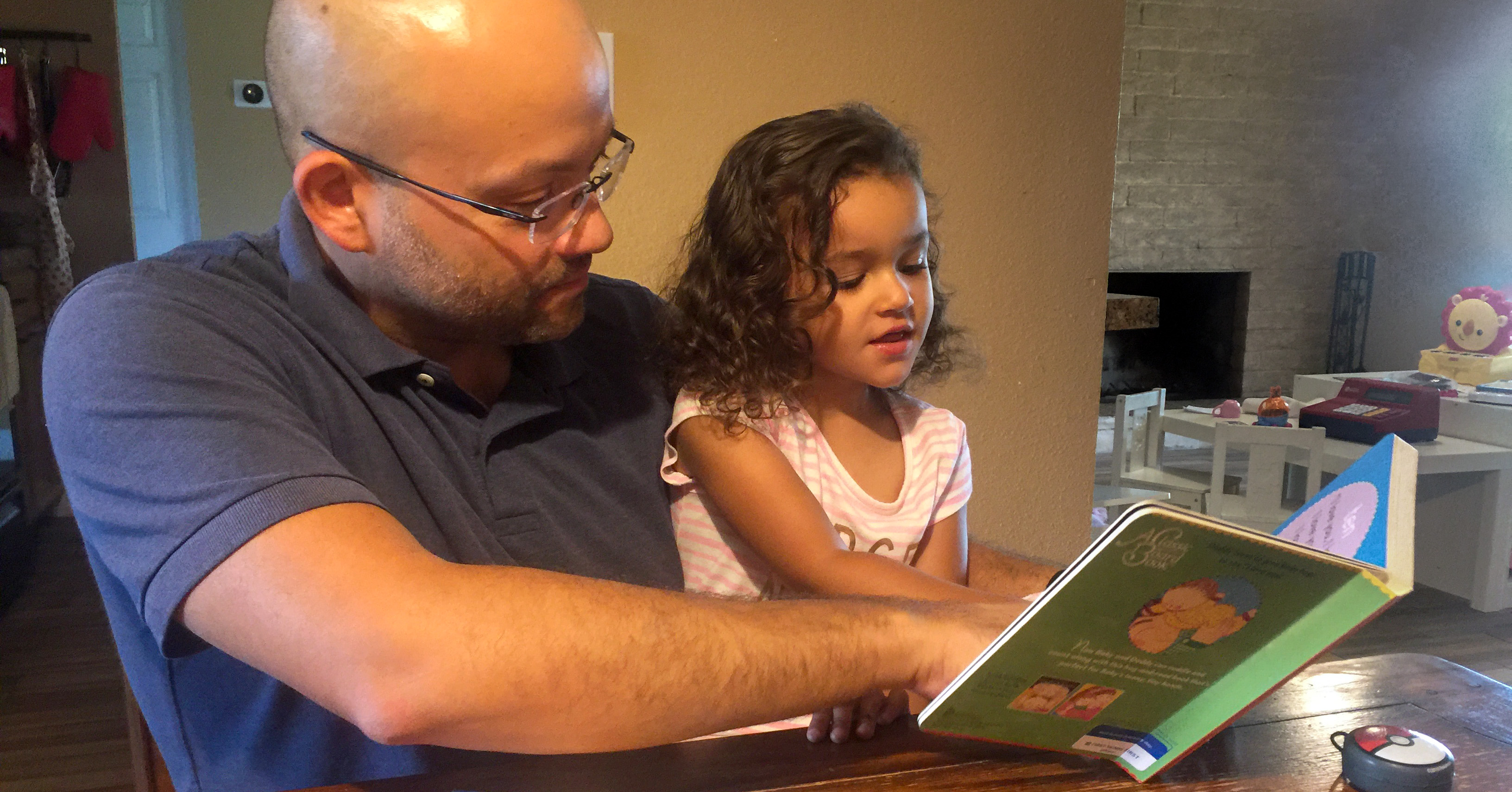 Dad reading book to young daugher