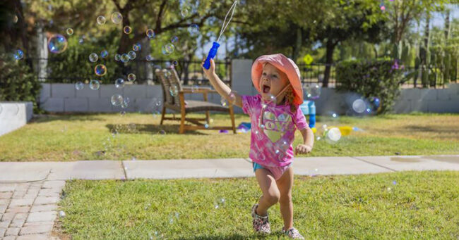 girl in pink bathing suit with bubble wand